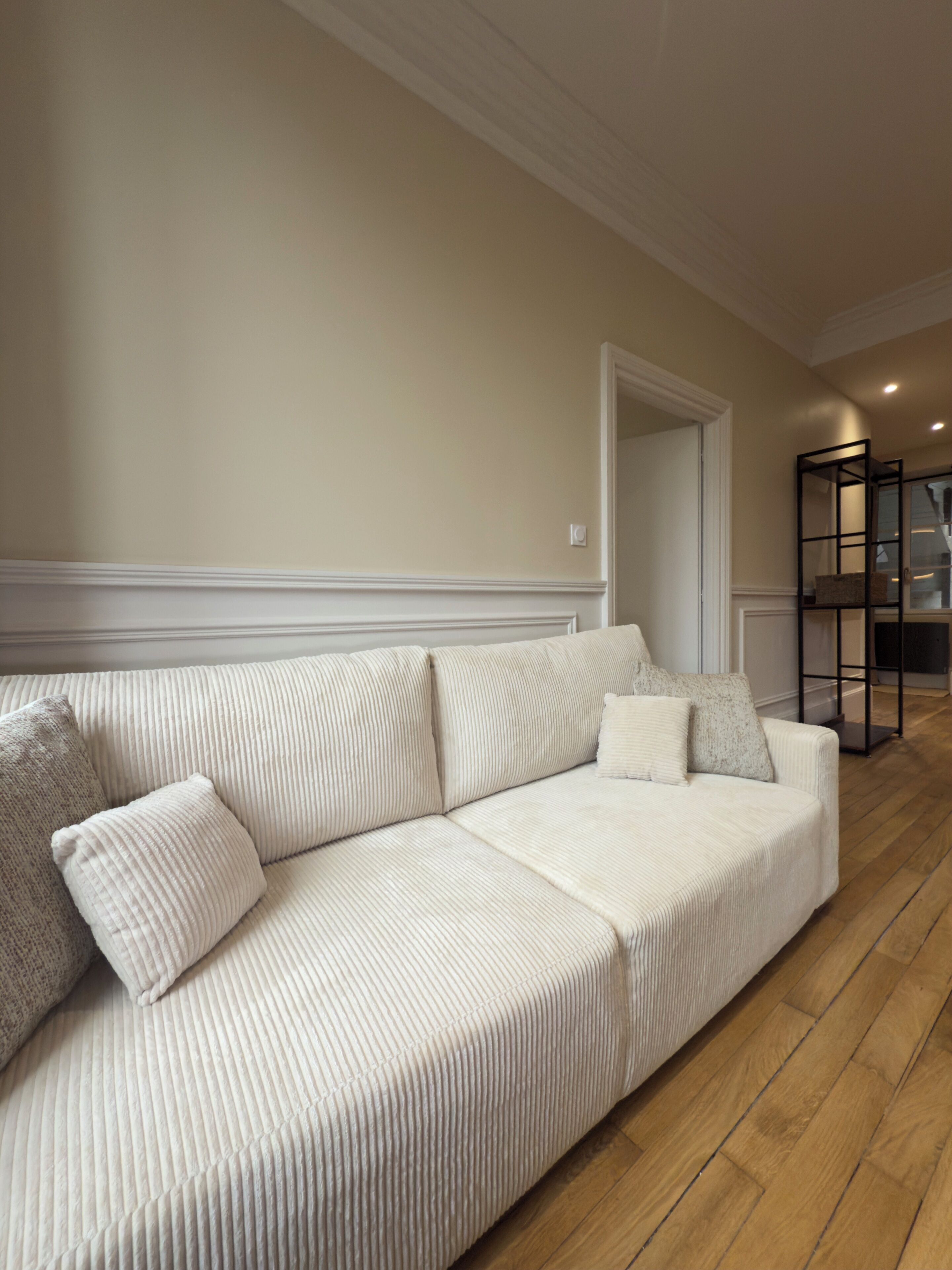 Ein weißes Sofa, ein Holzboden und eine weiße Tür im Hintergrund.