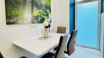 Ein moderner Essbereich mit einem weißen Tisch, braunen Stühlen und einem großen Wandbild mit Naturmotiven.