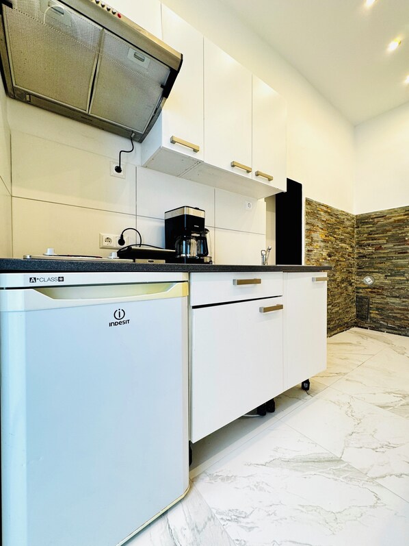 A modern kitchen with white cabinetry, a built-in oven, and a coffee maker.