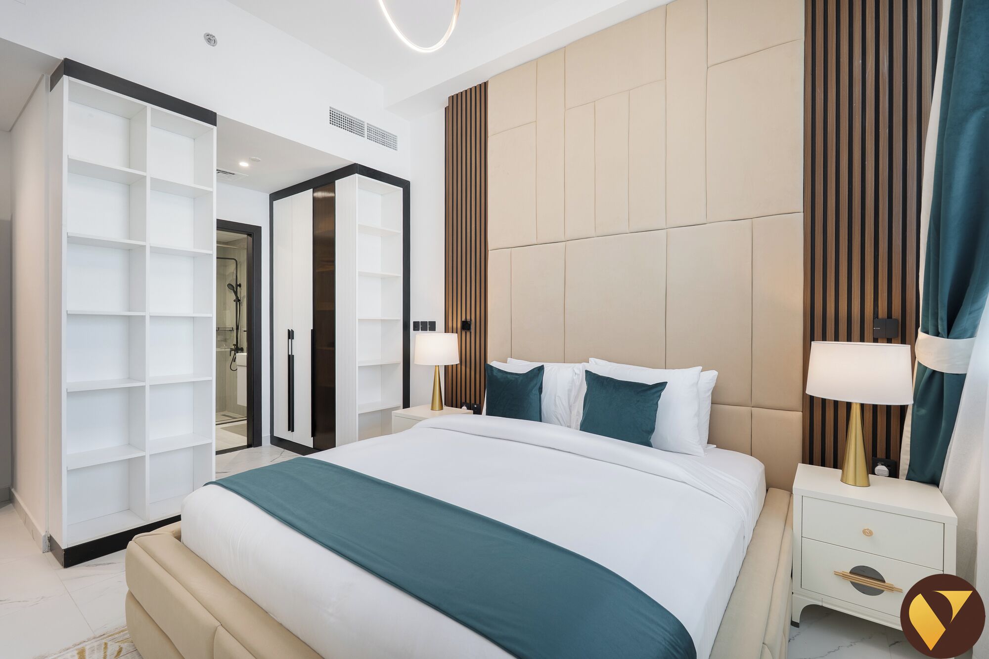 A modern hotel room with a large bed, a walk-in closet, and a bathroom with a glass shower enclosure.
