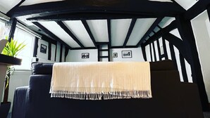 Une pièce chaleureuse avec un plafond haut, des poutres apparentes et une grande fenêtre.
