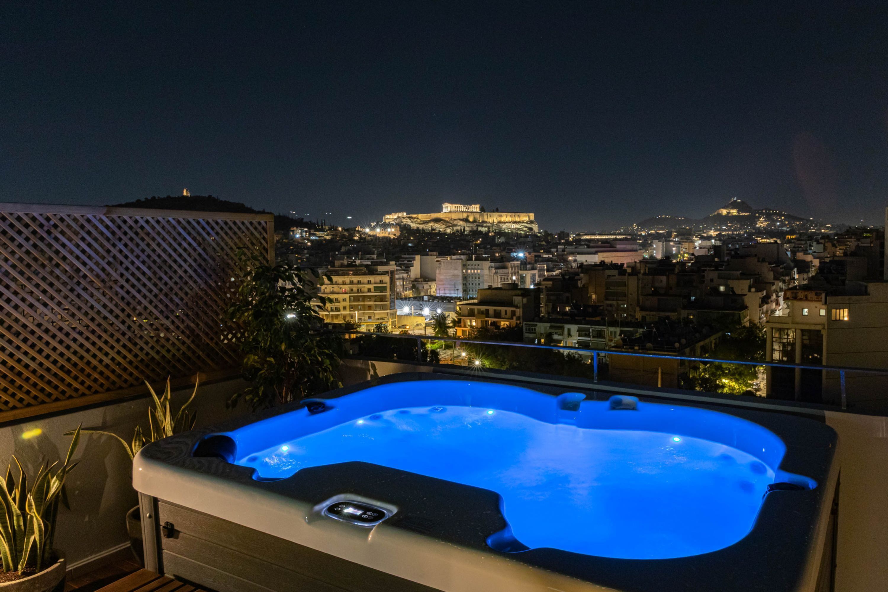 A hot tub on a balcony with a cityscape view, including a prominent building on a hill.