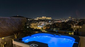 A hot tub on a balcony with a cityscape view, including a prominent building on a hill. - Acropolis Sky Retreat Jacuzzi 3BR Maisonette (Athens)