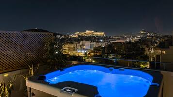 A hot tub on a balcony with a cityscape view, including a prominent building on a hill.