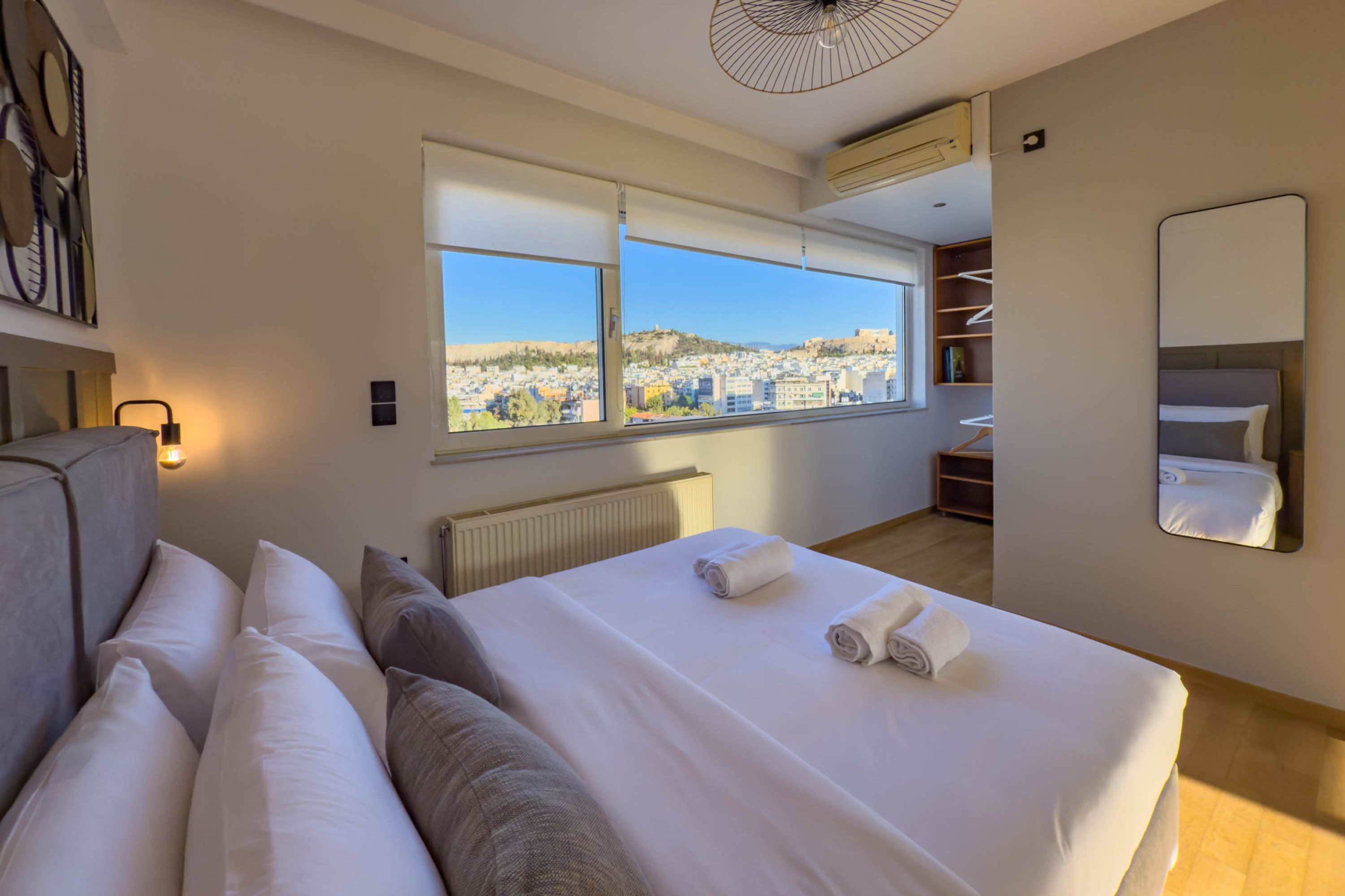 Une chambre d’hôtel moderne dotée d’un grand lit, offrant une vue sur la ville et comprenant une armoire intégrée.