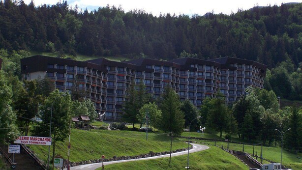 Un hotel de diverses plantes amb un disseny arquitectònic modern, situat en una zona verda i amb pendent.