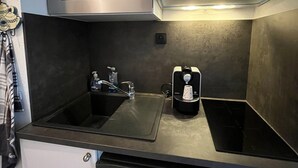 Una cuina compacta amb forn d'acer inoxidable, microones, un rentapeus i una campana extractora integrada.