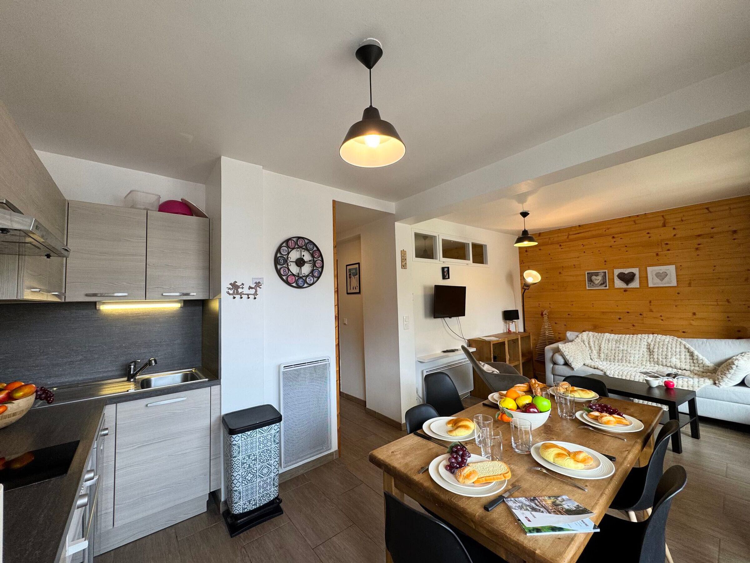 A modern kitchen with a dining area, wooden accents, and a cozy living space.