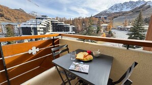 Un balcón con mesa, sillas y vistas a montañas y edificios.