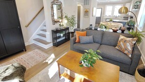 A modern living room with a sofa, coffee table, and a staircase leading to another level. - The Brightwood House - Family Living in the Heart of DC! (Washington)