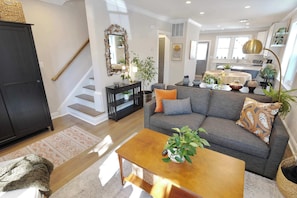Ein modernes Wohnzimmer mit Sofa, Couchtisch und einer Treppe, die zu einer weiteren Ebene führt.