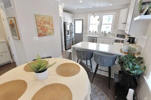 Eine moderne Küche mit weißen Schränken, einem Edelstahl-Kühlschrank und einer zentralen Kochinsel mit Barhocker.