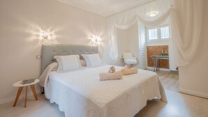 Een netjes ingerichte slaapkamer met een groot bed, nachtlampjes en een klein tafeltje met een tijdschrift.