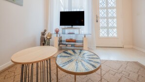 Een woonkamer met een televisie, een ronde salontafel en een bank.