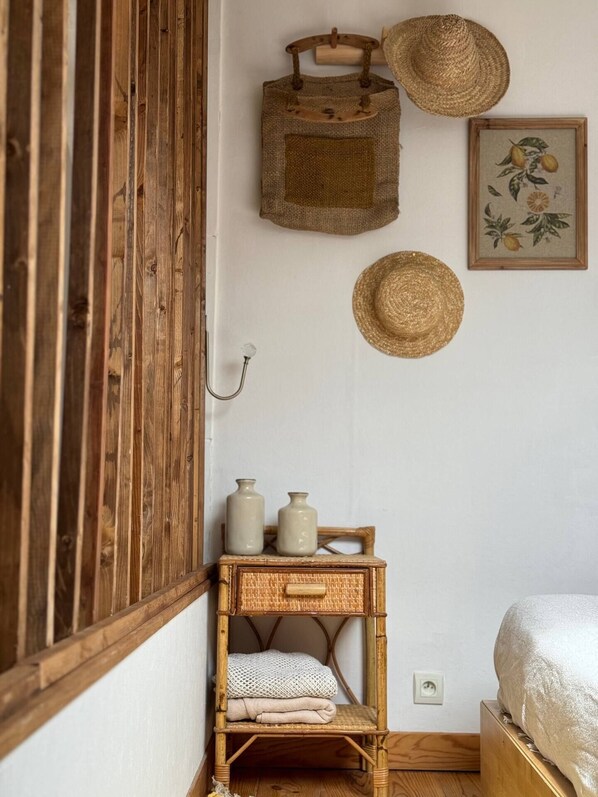 Una habitación rústica con un armario de madera, una cesta de mimbre, dos jarrones de cerámica y una cesta tejida en la pared.