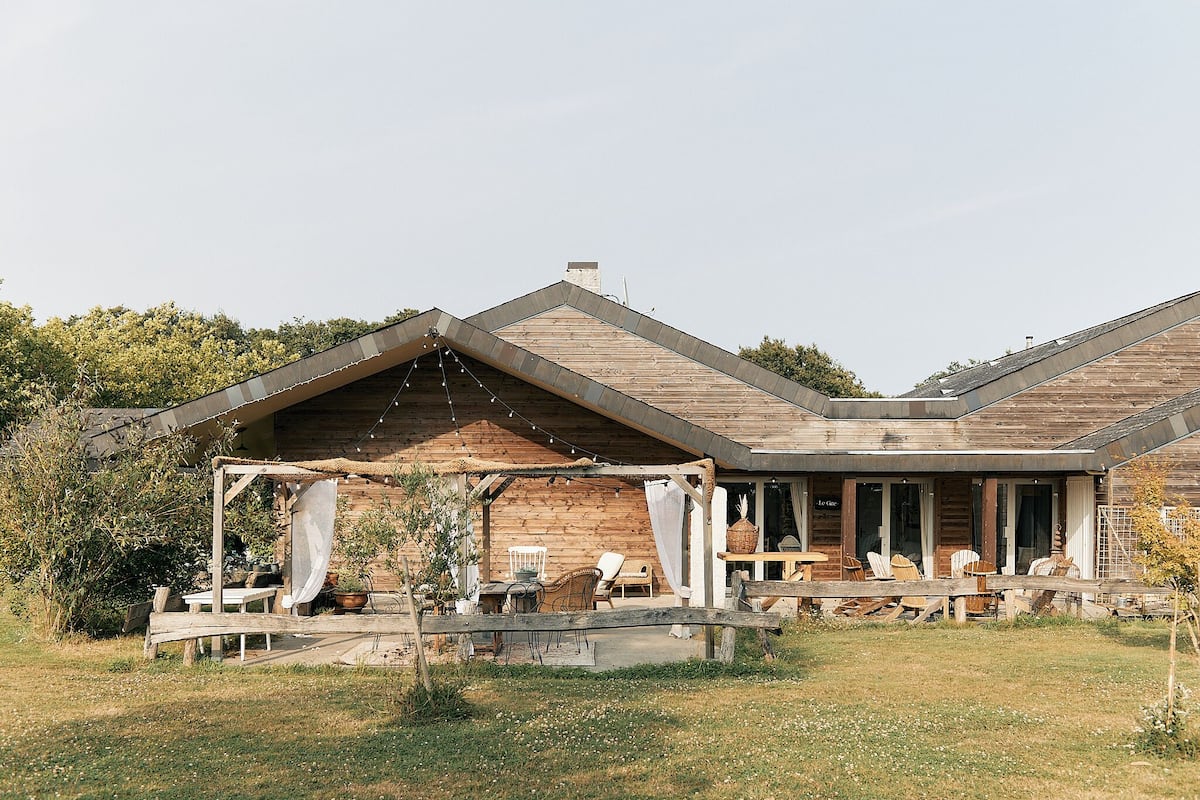 A rustic wooden building with a covered outdoor seating area, a dining table, and chairs.