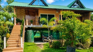 A two-story house with a green roof, a staircase leading to the entrance, and a covered parking area. - Lemon wood Cottage (Naobaricha)
