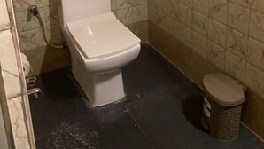A small bathroom with a toilet, a trash bin, and a shower area. - Lemon wood Cottage (Naobaricha)