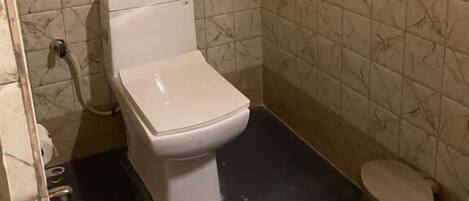 Un baño pequeño con inodoro, un cubo de basura y zona de ducha.