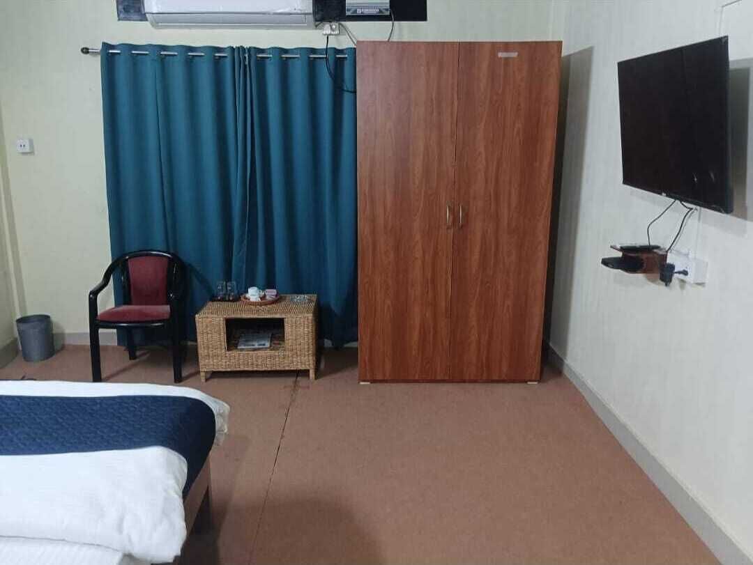 Et hotelværelse med seng, garderobeskab, fjernsyn, stol og lille bord.