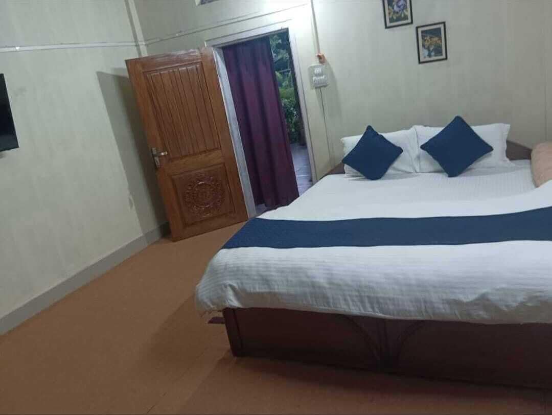 A bedroom with a bed, a wooden wardrobe, and a door leading to a balcony.