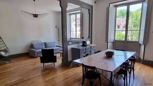 A modern living space with a dining area, a sofa, a chair, and a kitchen counter. - L'atelier du Centre D'ax les Thermes (Ax-les-Thermes)