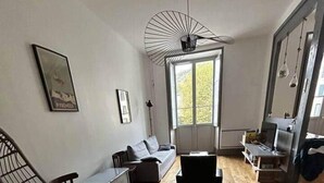 A modern living room with a wooden floor, a sofa, a chair, and a ceiling fan. - L'atelier du Centre D'ax les Thermes (Ax-les-Thermes)