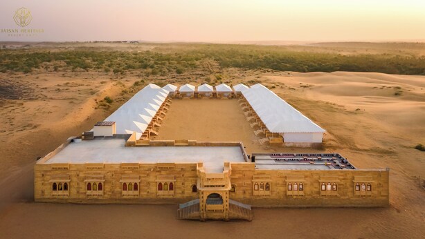 Un campamento en el desierto con un edificio extenso, un patio central y varias tiendas de campaña.