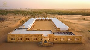 A desert camp with a long building featuring a central courtyard and multiple tents.