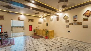 Un hall de hotel con suelo estampado, una recepción y cuadros en las paredes.
