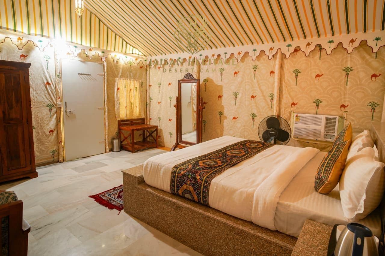 A spacious room with a large bed, a wooden wardrobe, a mirror, and a fan.