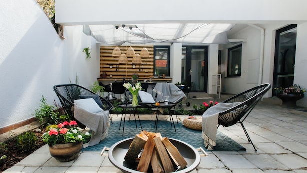 Een terras met een vuurkorf, tuinmeubilair en een eethoek.