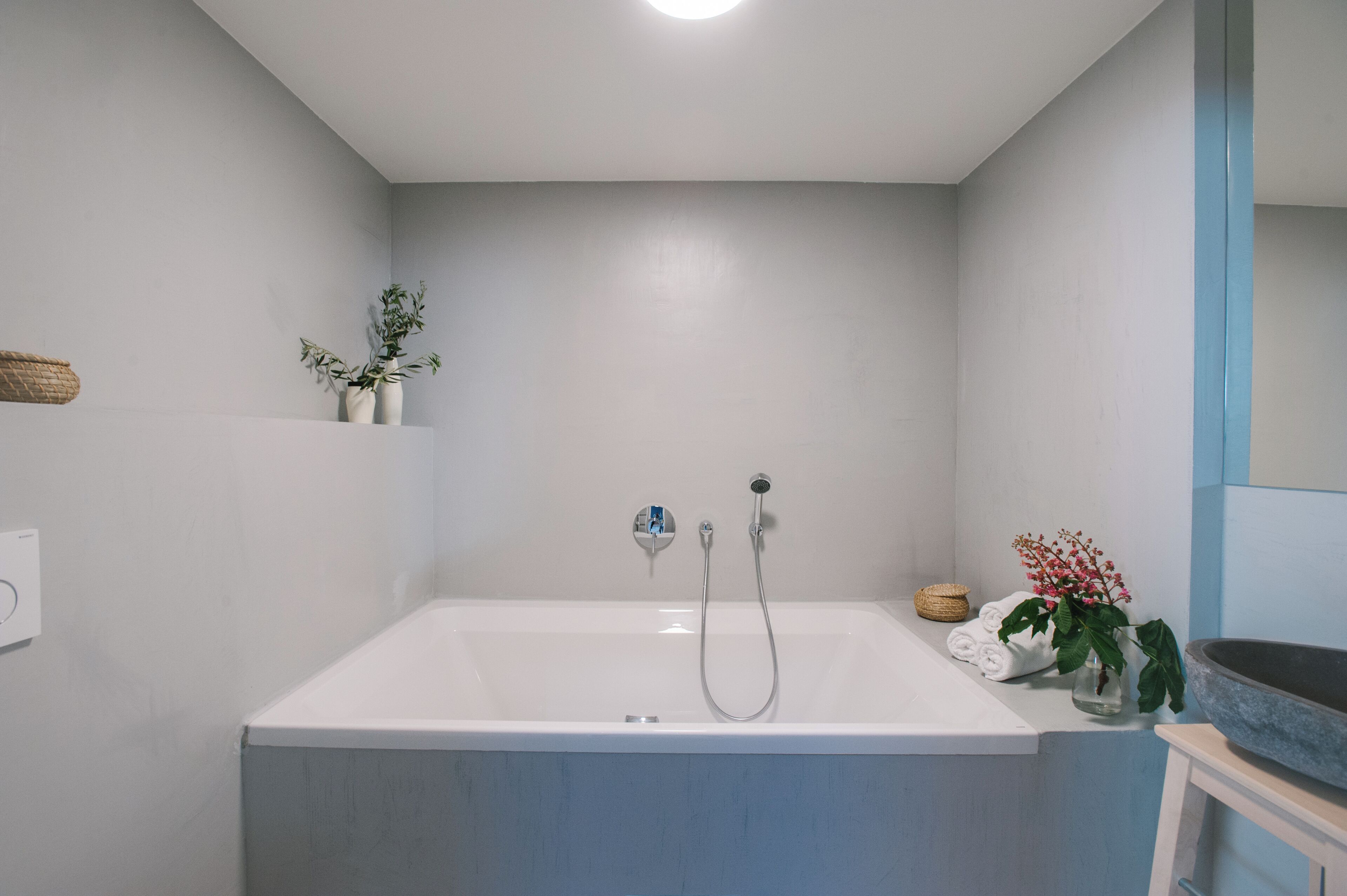Une salle de bain moderne avec une baignoire, un porte-serviettes et une petite plante.