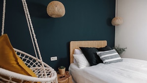 Een slaapkamer met een bed, een hangstoel en twee wandlampen.
