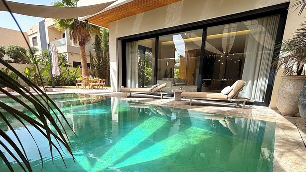 A modern outdoor pool area with lounge chairs and a dining table. - Palais Oyena (Marrakech)
