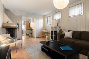 Una sala de estar con chimenea, un sofá, una mesa de centro y un comedor con una silla y una mesa.