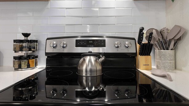 A kitchen with a stainless steel stove, a kettle, and a spice rack. - CozyCottage_Sleeps8_Near Plaza and KU_and Shopping (Mission)