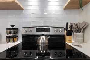 A kitchen with a stainless steel stove, a kettle, and a spice rack. - Family Fave_Sleeps8_Near Plaza and KU_Shopping (Mission)