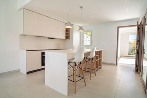 A modern kitchen with white cabinetry, a central island, and bar stools. - A beautiful apartment facing the Caribbean Sea in a prestigious residence (sint maarten)