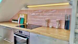 Une cuisine moderne avec un plan de travail en bois, des appareils en acier inoxydable et un dosseret carrelé rose.