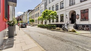 Une rue bordée d’immeubles, avec des voitures garées et un vélo.
