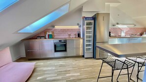 Une cuisine moderne dotée d’un four encastré, de meubles en acier inoxydable, d’un réfrigérateur et d’une mezzanine avec une lucarne.