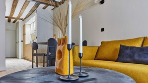 A modern living room with a yellow sofa, a round table with candles, and a kitchen in the background. - Charming apartment Center of Paris/Montorgueil (Paris)