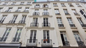 A row of white, multi-story buildings with balconies and numbered windows. - Charming apartment Center of Paris/Montorgueil (Paris)