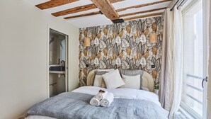 A bedroom with a bed, a window with curtains, a wooden ceiling, and a wall with a leaf pattern. - Charming apartment Center of Paris/Montorgueil (Paris)