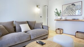 Una sala de estar moderna con un sofá gris, una mesa de centro redonda y un cuadro en la pared.
