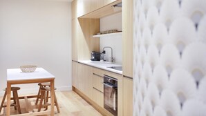 Una cocina compacta con encimera blanca, armarios de madera y horno integrado.