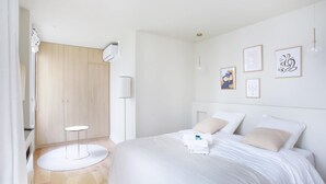 Un dormitorio moderno con una cama grande, una mesita redonda pequeña y obras de arte en la pared.