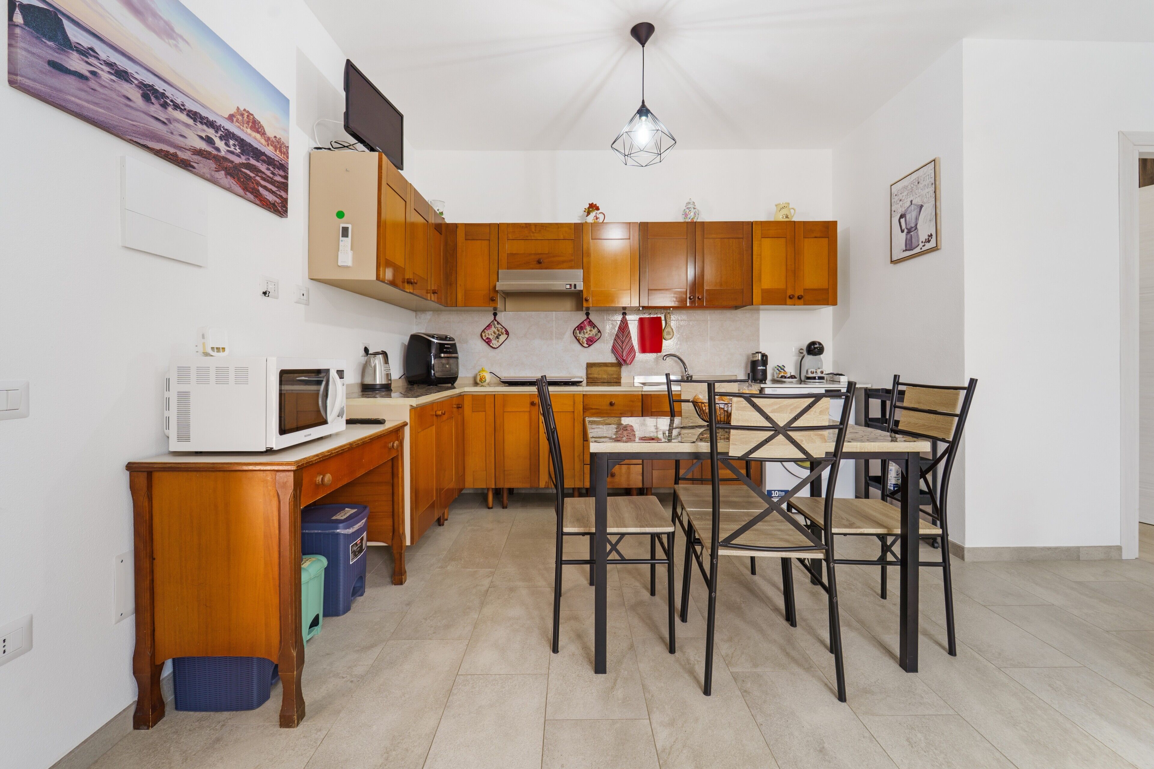 Une cuisine compacte avec des meubles en bois, un four à micro-ondes, un grille-pain et une table à manger avec des chaises.