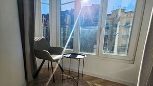 A corner room with a large window, a chair, and a small table. - Apartamentos Ciudadela Superior 3000 (Jaca)